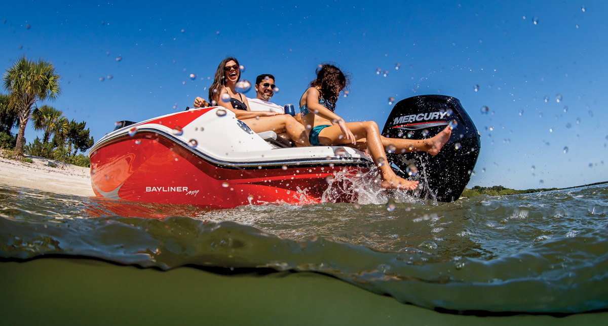 Three people on a red boat enjoying a sunny day with water splashing.
