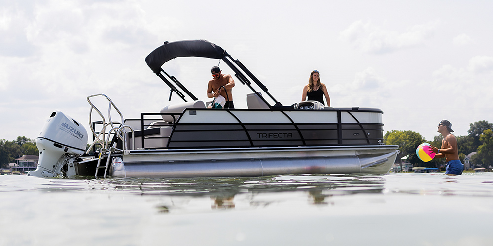 black and white Trifecta 22UL LE pontoon sitting idly in the water