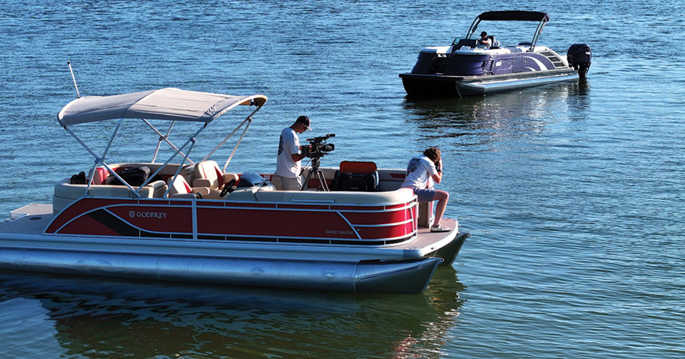 Two boats on a body of water, with people on board a red pontoon and a black motorboat.