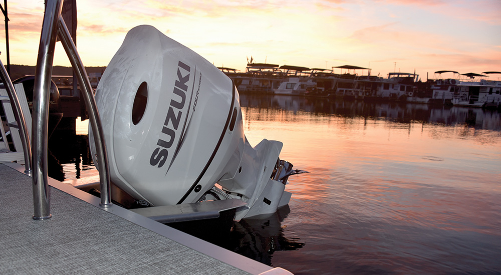 Suzuki outboard motor on a boat at sunset in a marina.