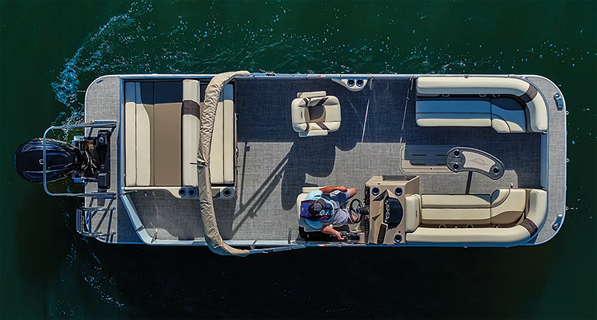 Top aerial drone-shot outdoor landscape photograph of the SunCatcher Select 324 SL pontoon motorboat vehicle showcasing the male driver seated in the driver's seat as the vehicle is out in the water
