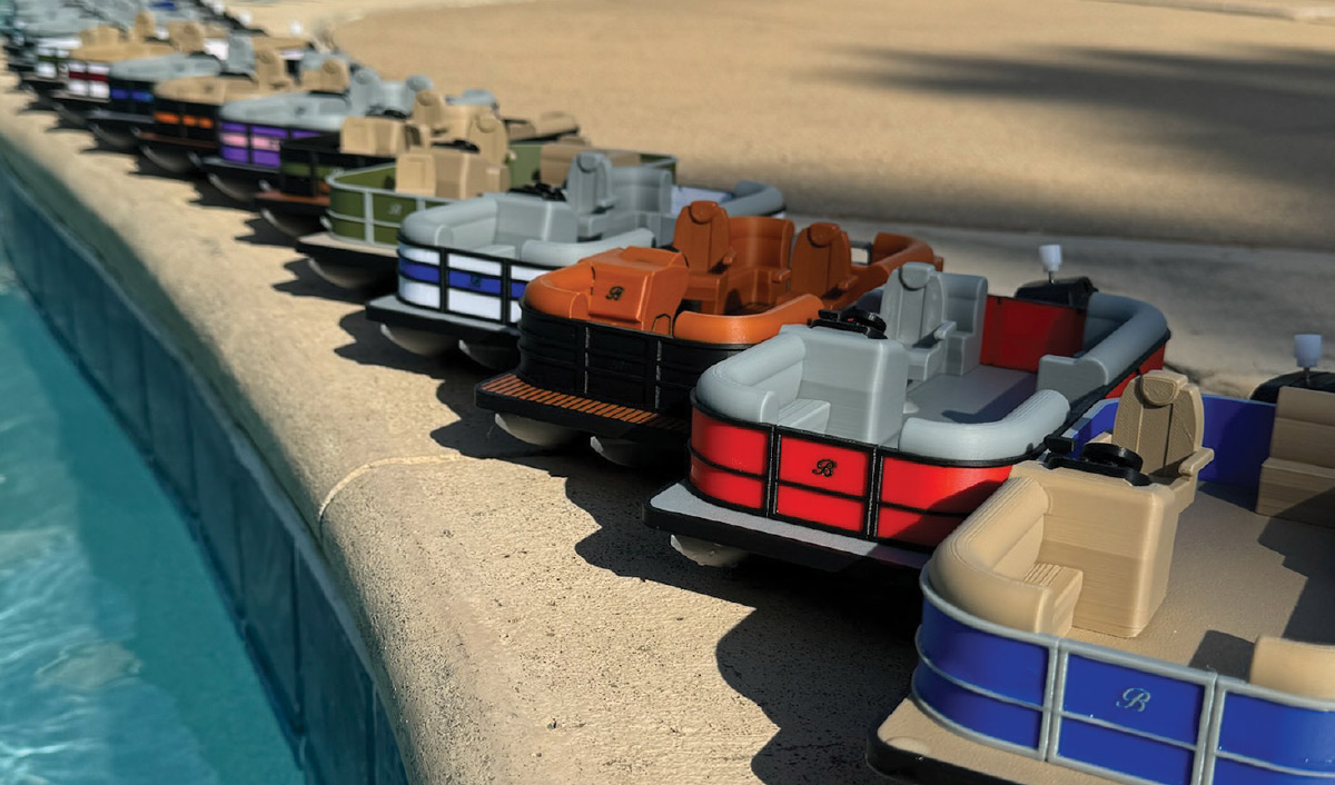 closeup of different colored 3D printed miniature pontoons lined up against edge of pool