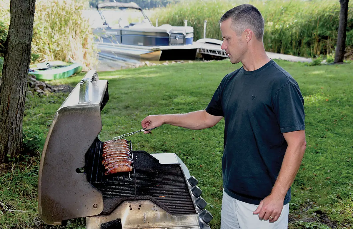 a man tends to links on a BBQ