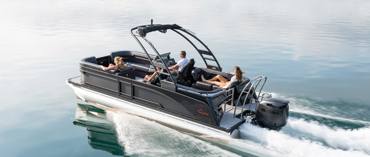 Pontoon boat with three people on calm water, equipped with a Suzuki outboard motor.