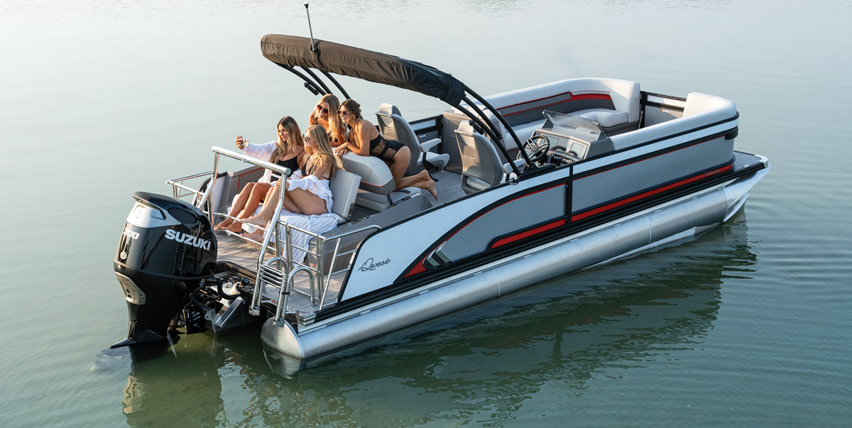 Pontoon boat on water with five people seated, featuring a canopy and a Suzuki outboard motor.