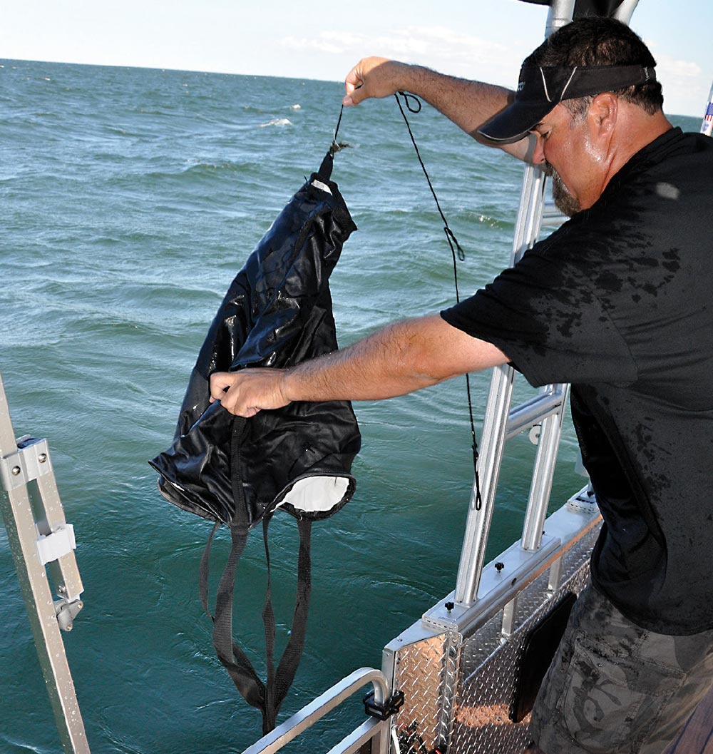 man lifting drift sock from water