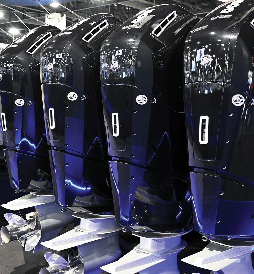 Four black outboard motors in a row with metallic propellers.
