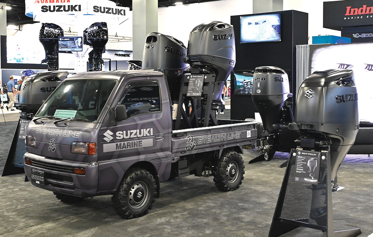 Small utility truck at a marine exhibition with Suzuki outboard motors.