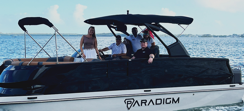 A motorboat named "Paradigm" with five people aboard on a body of water.