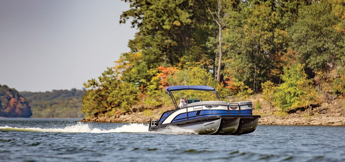zoomed out view of a blue and black Bennington pontoon in the water