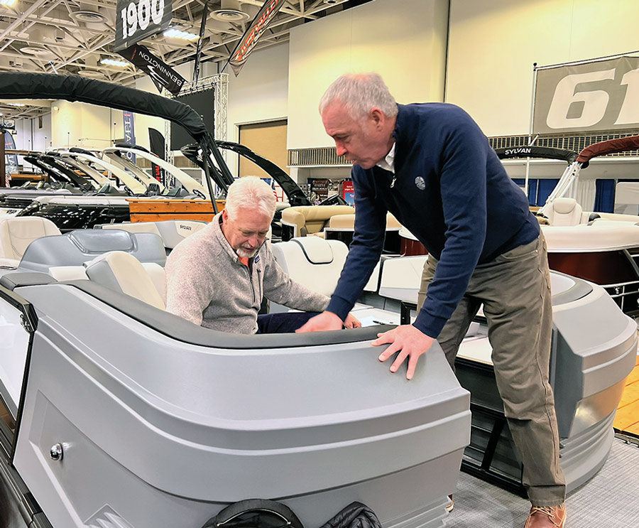 one man sits in a passenger seat of a Sylvan pontoon as another man observes the bench material
