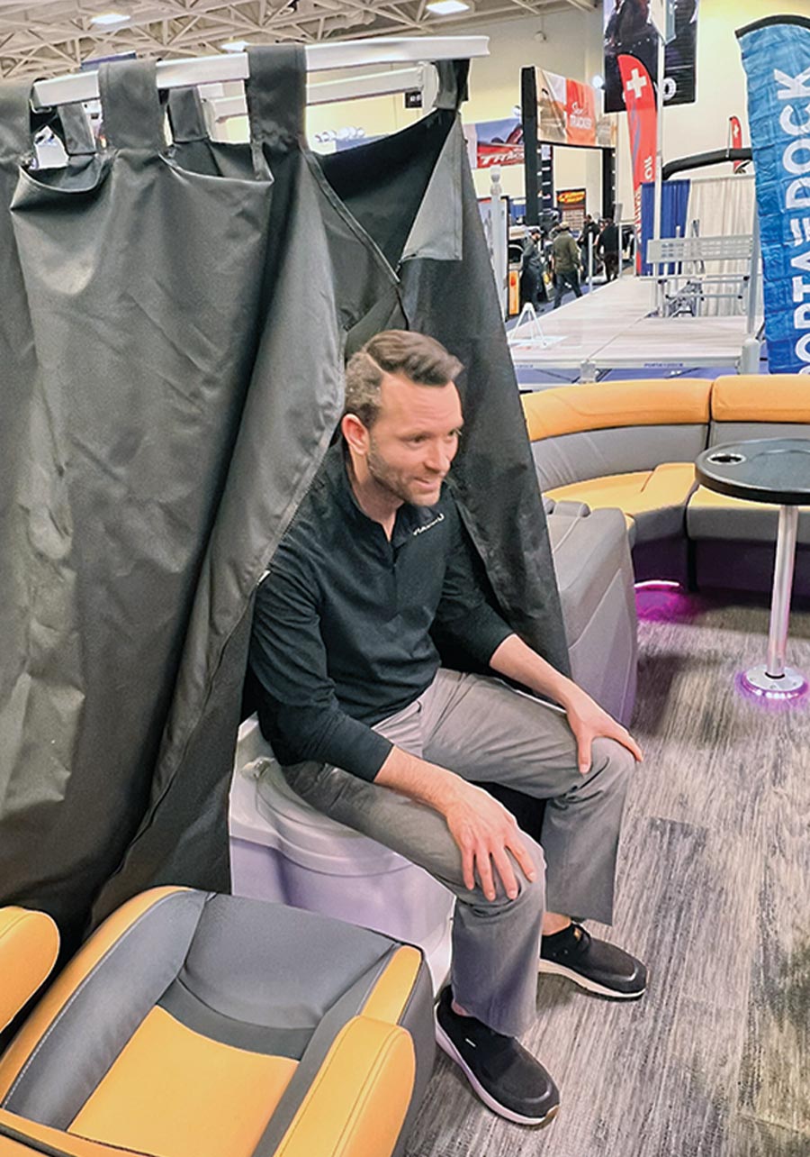 a man demonstrates the standard height of the slide out toilet on a Viaggio pontoon