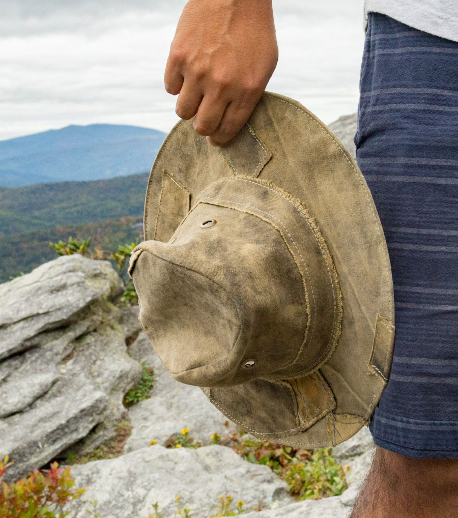 man holding Real Deal Brazil Tarp Hat near his thigh