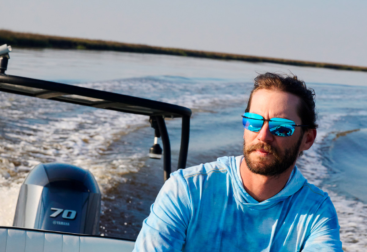 man wearing blue polo and Shady Ray Sunglasses while driving pontoon