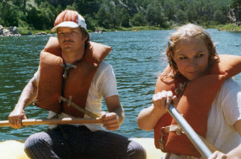 man and woman wearing life jackets while rowing boat