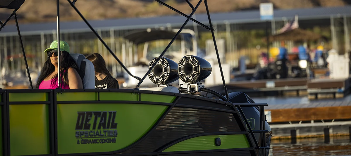 partial view of a green and black Godfrey pontoon parked at a dock