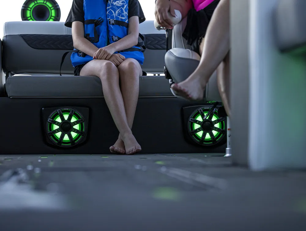 people sitting in the seats of a pontoon with focus on the speakers installed underneath