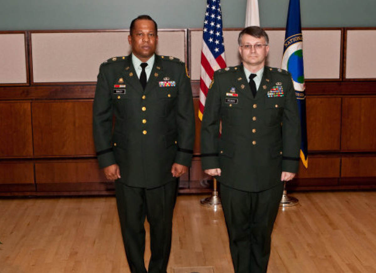 two men in green army uniforms standing side by side for a photo