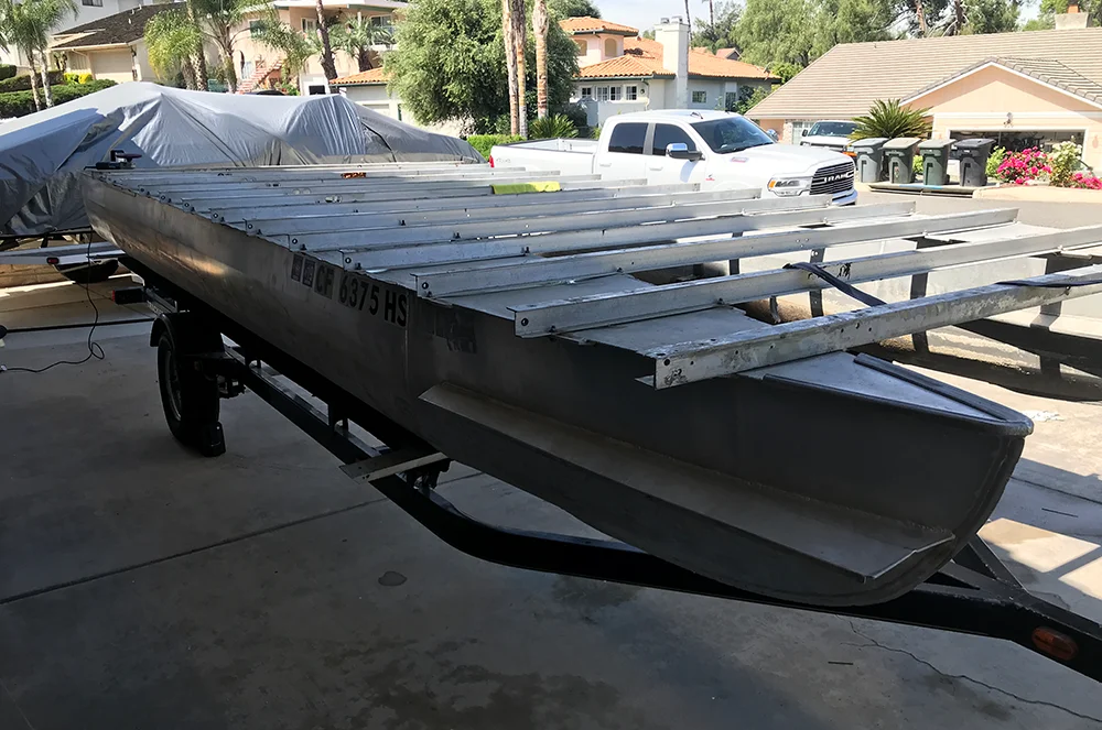 A close-up view of the aluminum decking and hull of a pontoon boat, showing the process of boat rebuilding.