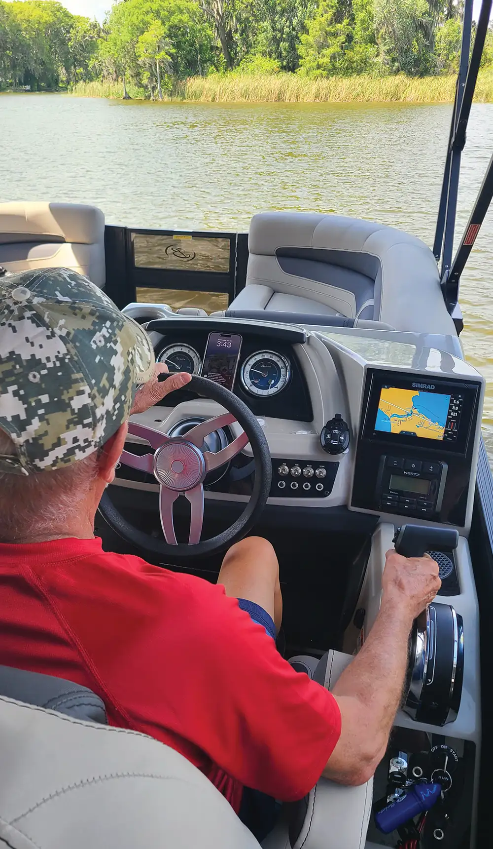 Person steering a boat with a navigation screen showing a map.