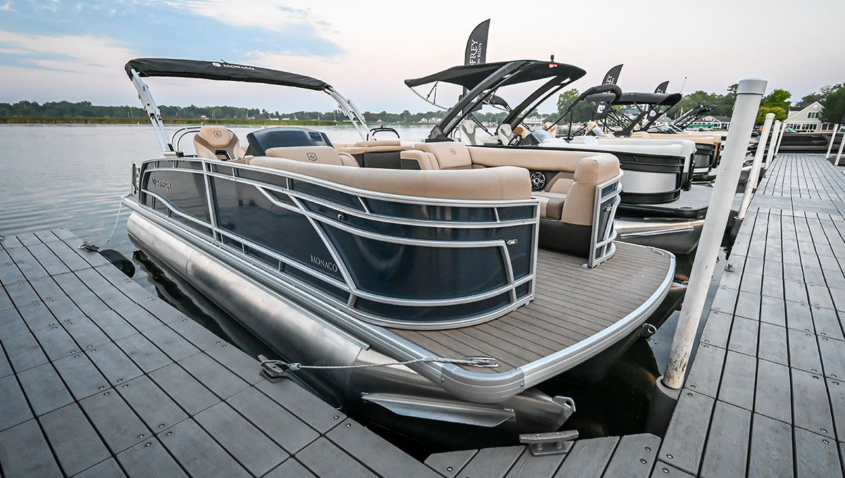 starboard side angled view of a line of different colored Godfrey Marine pontoons parked at a pier
