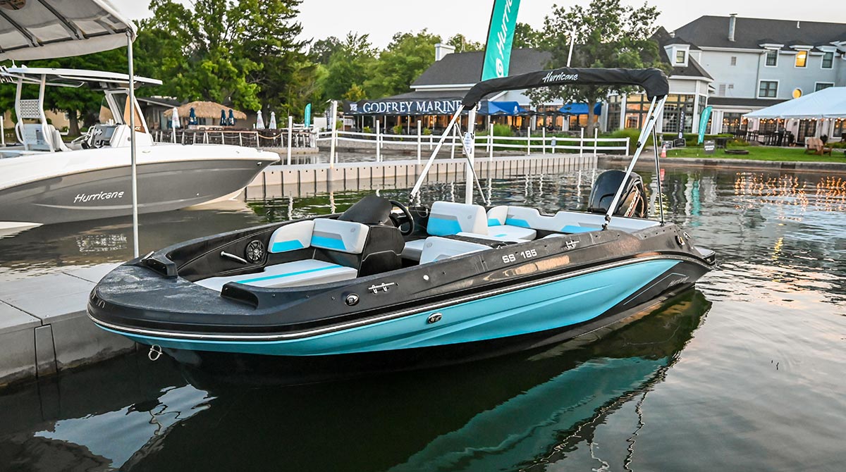 Port side view of a black and light blue Hurricane deck boat