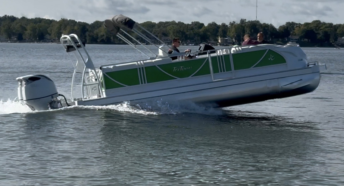 full starboard side view of a green and white JC TriToon pontoon sailing on water