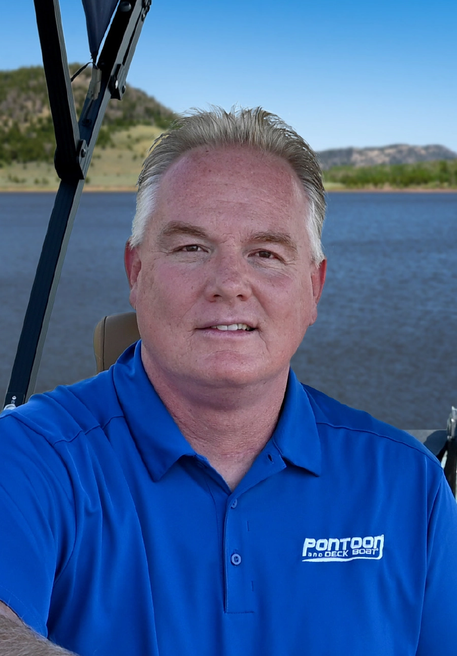 Photograph headshot of Brady L. Kay, a man grinning faintly dressed up in a blue Pontoon and Deck Boat polo top shirt