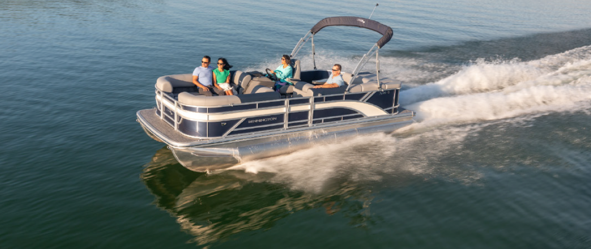 A group of four people inside a Bennington 20SL w/Torqeedo Electric Motor pontoon motorboat vehicle as it is being driven out on the water