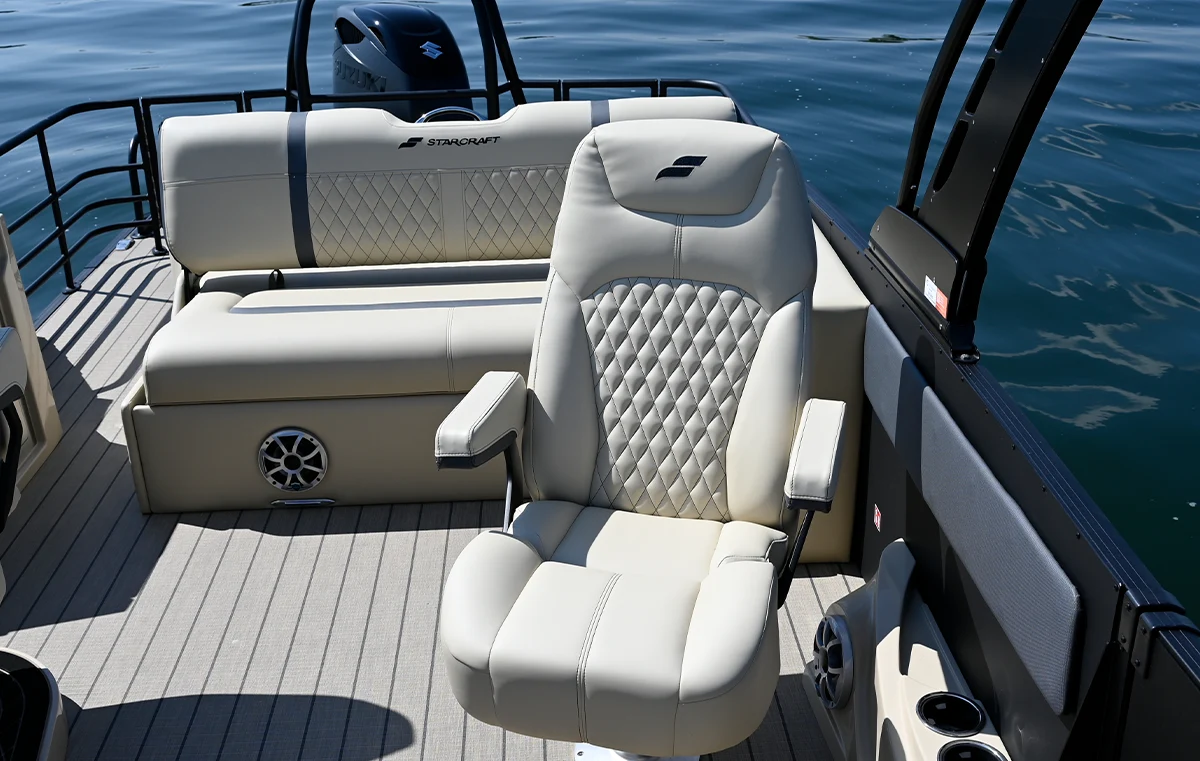 A high-back, cream-colored marine captain's chair with diamond-stitch embroidery and flip-up armrests on a Starcraft pontoon boat.