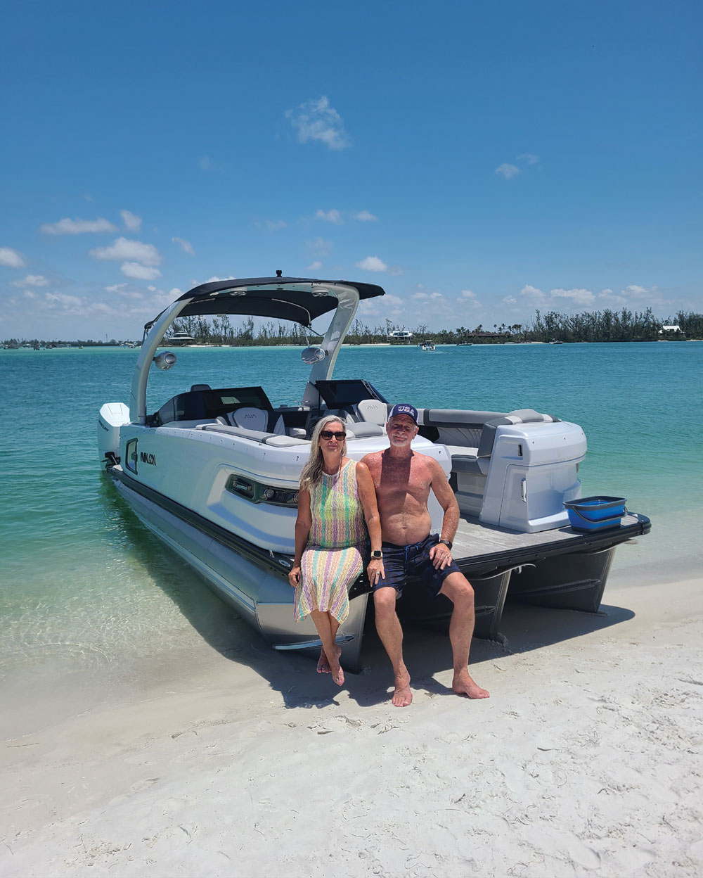 man and woman sitting on the edge of a boat docked on shore