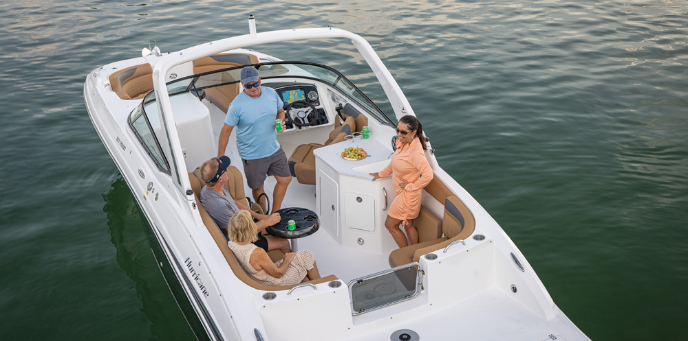 Overhead view of a white Hurricane deck boat. Four people socialize around a small table and a built-in refreshment center featuring a countertop and sink.