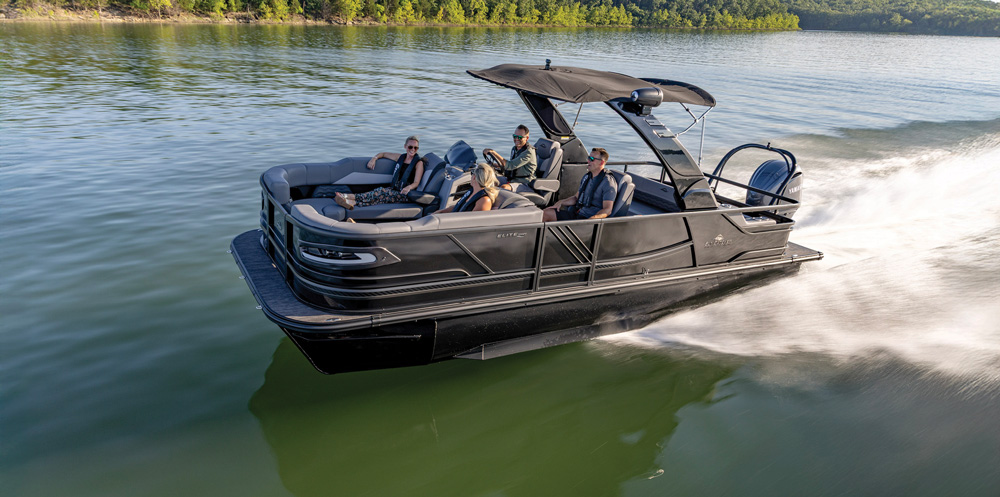 An all-black SunChaser pontoon boat moves quickly across the water. The boat features a matching black bimini and grey luxury seating for the passengers.