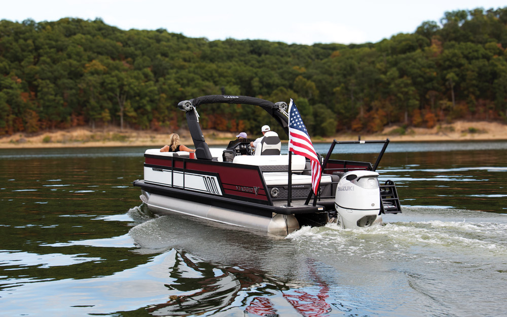 A rear view of a Viaggio pontoon boat with a red and white exterior. An American flag is mounted at the stern next to a white Suzuki outboard engine.
