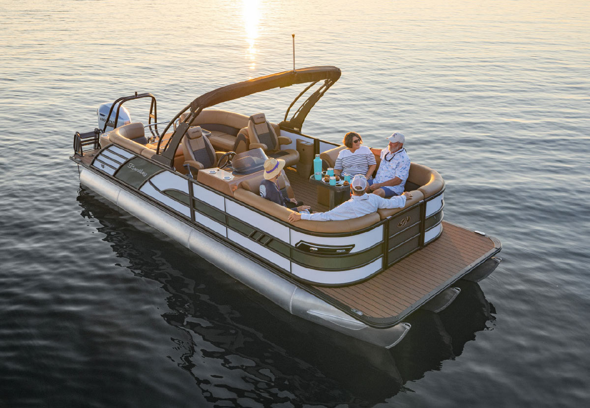 Overhead view of four adults relaxing on a Bentley pontoon boat during a calm sunset on the water.