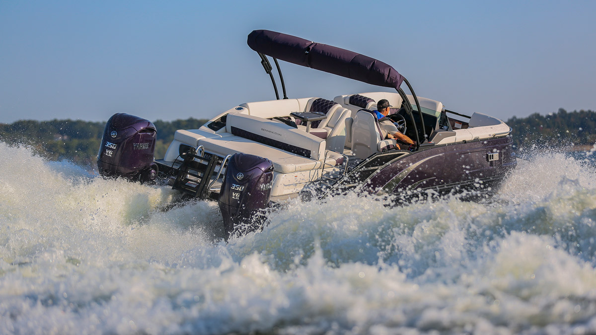 A purple Bennington pontoon boat with twin Yamaha 350 V6 engines cruises at high speed, kicking up a dramatic white water wake on a bright, sunny day.