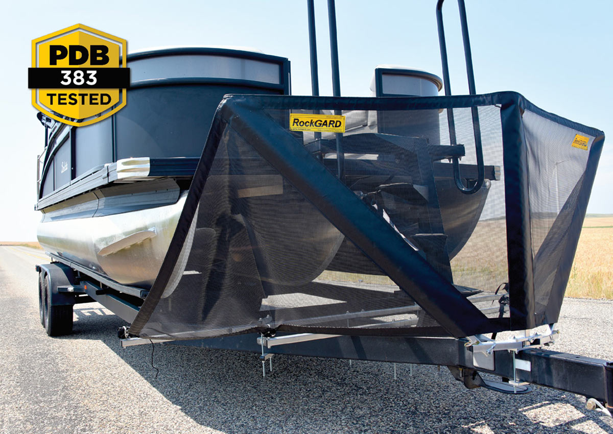A pontoon boat on a trailer equipped with a black RockGARD mesh towing shield to protect the hulls from road debris. A "PDB 383 Tested" logo is in the corner.