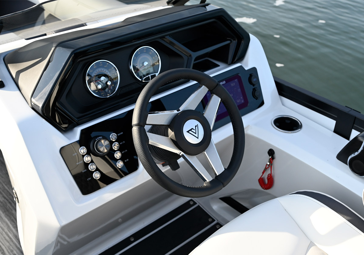 Detailed view of a modern white boat console featuring a black steering wheel, two analog gauges, and a touchscreen display.