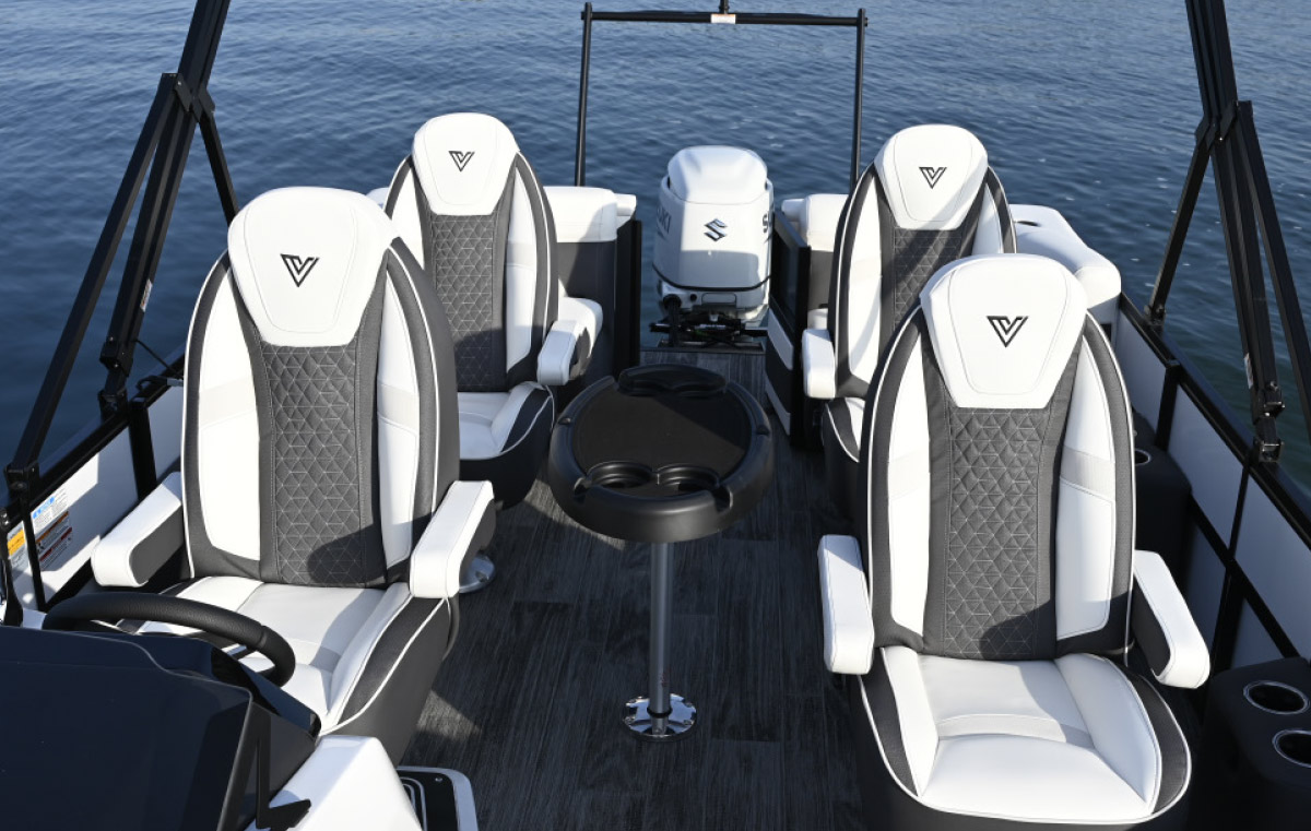 Interior view of a boat deck featuring four high-back white and grey swivel chairs and a central black pedestal table with cup holders.