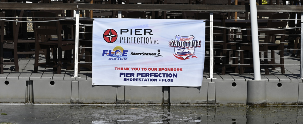 A banner on a dock fence thanks sponsors Pier Perfection, ShoreStation, and Floe, featuring the official Pontoon Shootout Boat Test 2026 logo.
