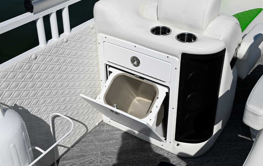 View of a white upholstered seat base with an integrated, tilted-out trash receptacle. The interior side panel features white diamond-stitched padding, and two stainless steel cup holders are visible on top of the seat.