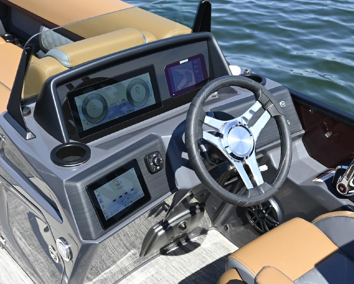 Close-up of a modern boat helm featuring dual digital touchscreen displays, a GPS unit, and a stainless steel steering wheel.