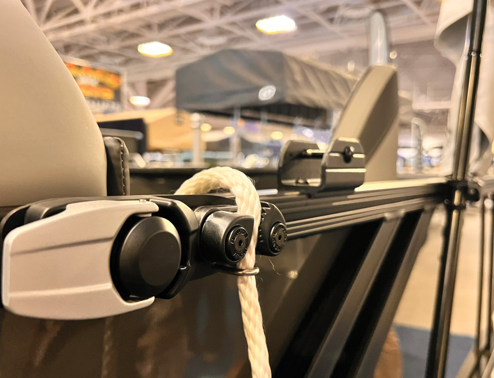 A close-up of a rope cleat and docking line system mounted on the black railing of a boat, demonstrating the secure attachment of a thick, white braided marine rope.
