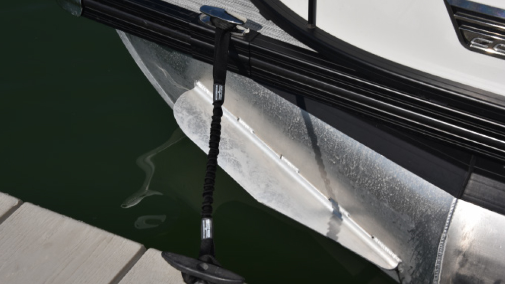 A black bungee dock line attached between a boat cleat and a dock cleat to provide shock absorption.