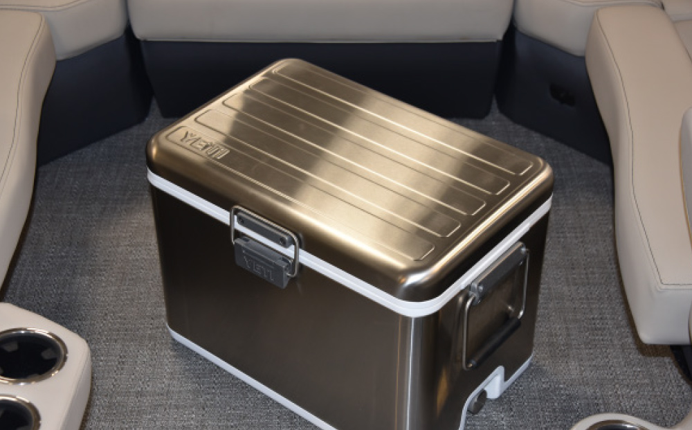 A stainless steel Yeti V Series cooler positioned in the center of a boat's seating area.