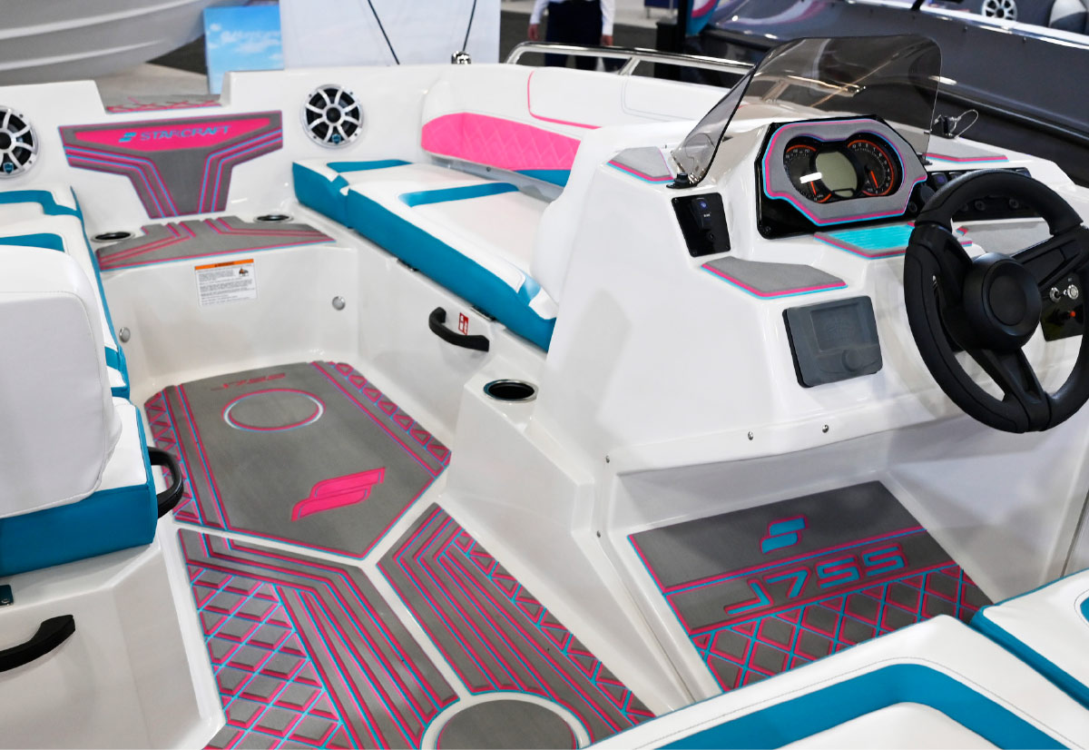 Interior cockpit of a Starcraft J7SS boat showing grey patterned flooring with pink and blue accents and white upholstery.