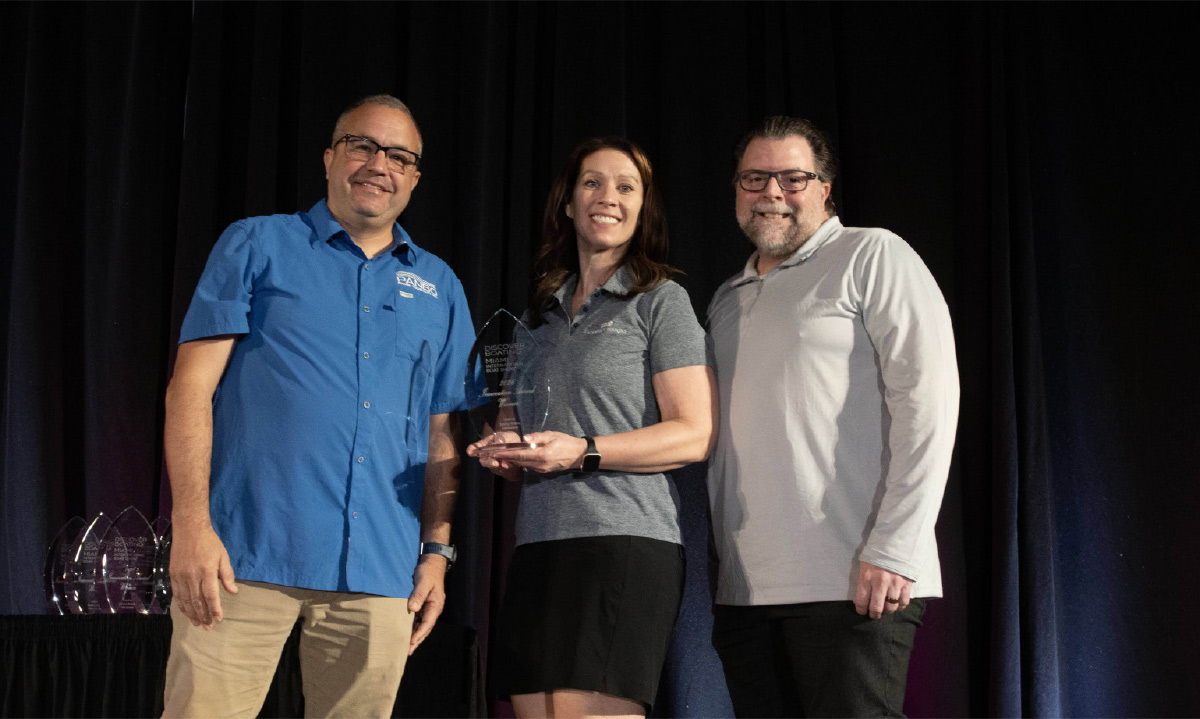 Three professionals stand on stage at the 2026 Miami Innovation Awards; a woman holds a glass trophy with others behind her.