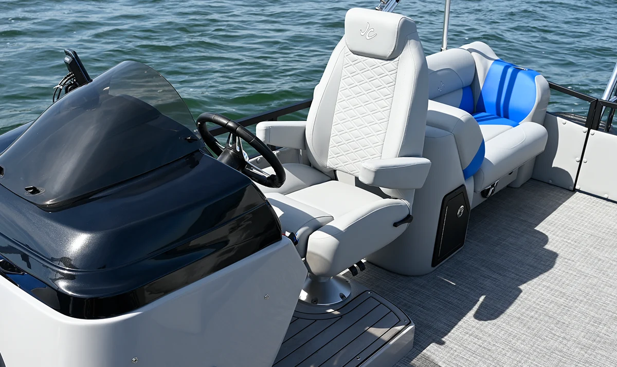 A spacious and modern living room suite at Oakwood Resort, featuring a charcoal grey sofa, hardwood floors, and large windows with white blinds overlooking Lake Wawasee