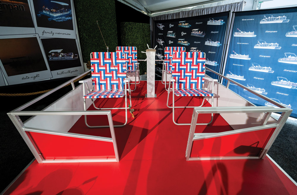 Overhead view of a boat display featuring a red deck, white railings, and four red, white, and blue woven lawn chairs.
