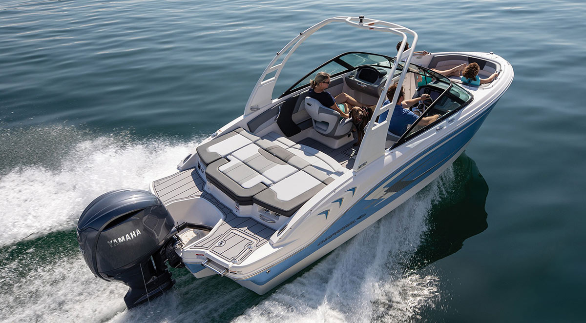 High-angle view of a family and their dog cruising on clear blue water in a Chaparral motorboat equipped with a white tower and a Yamaha outboard motor.